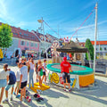 Ein Bungee Trampolin von Happy Fun zum mieten, viele Kinder und Teenager in einer Warteschlange wollen hüpfen.