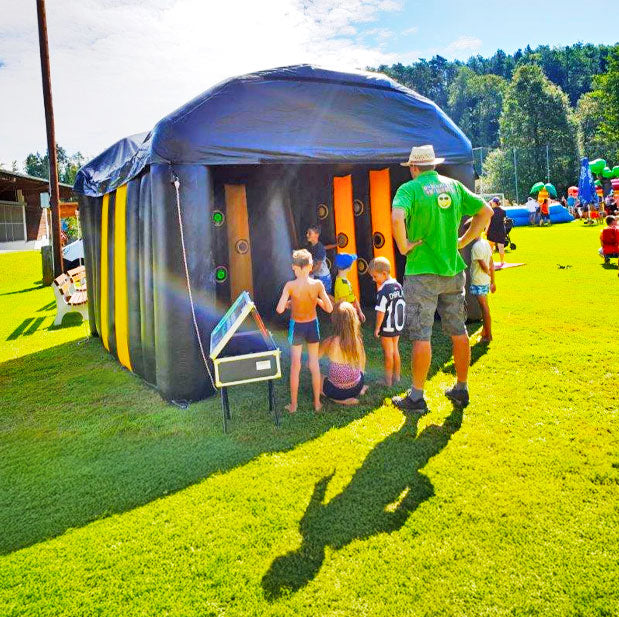 Kleine Kinder die in einer Buzzer Arena spielen, und Kinder die von aussen zusehen mit einer Aufsichtsperson