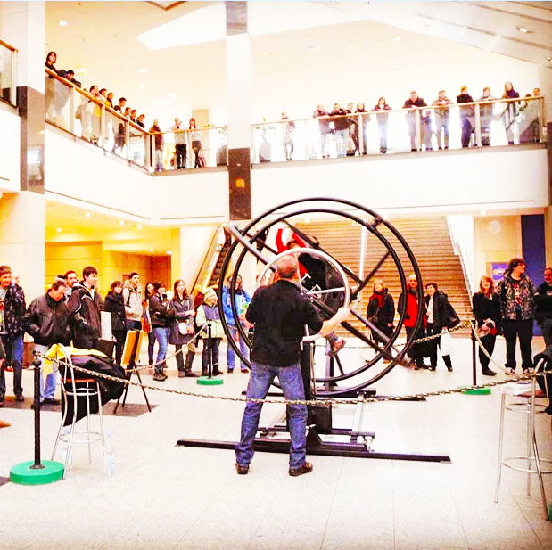 Ein Mann der einen Aerotrim mit einer Person in dem Sitz mit dem Antriebsrat bewegt und sehr viele Zuschauer