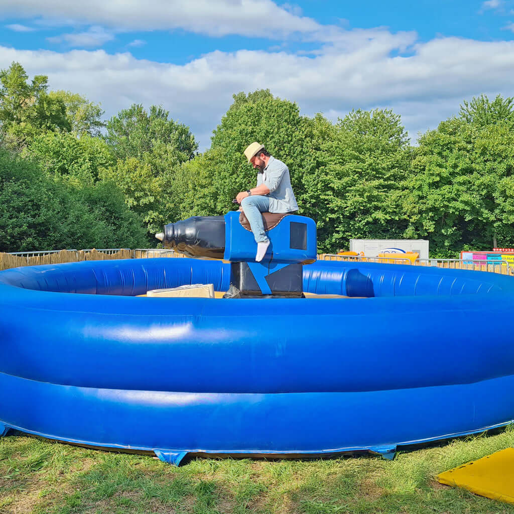 Ein Mann mit Hut reitet einen Rodeo - Akkuschrauber in einem blauen aufblasbaren Becken.