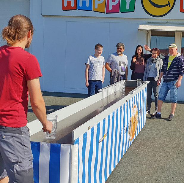 Erwachsene beim Bierkrugschiebn im freien.