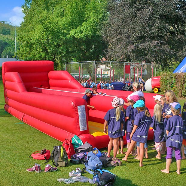 Kinder auf einem Fest im freien in einem Bungee Run mit Seilen.