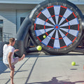 Ein Mann schiesst auf ein aufblasbares Fussball-Dart mit einem Gelben Ball.