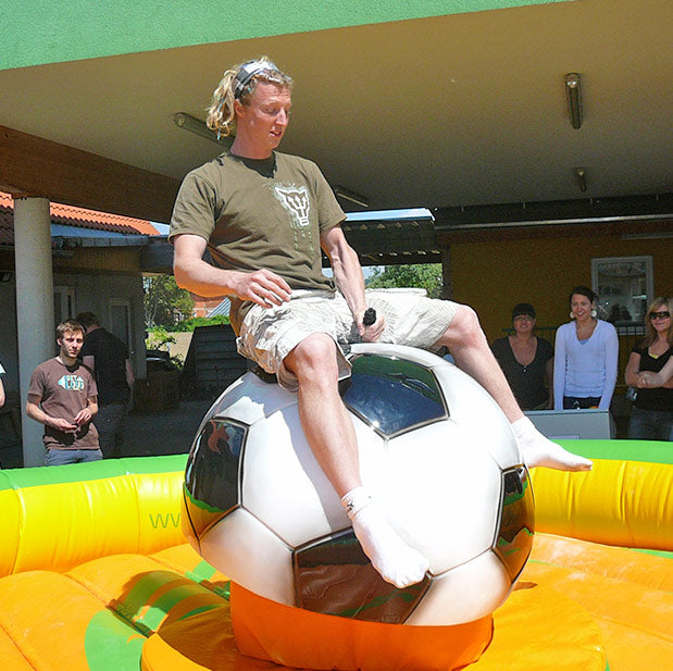 Erwachsener Mann in kurzen Hosen auf einem Fussball-Rodeo mit Zuschauern.