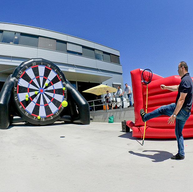 Ein Mann beim schiessen auf ein grosses Fussball-Dart.