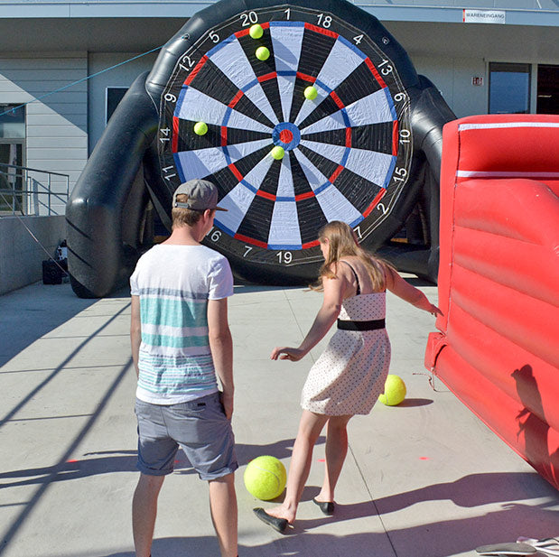 Frau die versucht einen ball auf ein Fussball-Dart zu schiessen.