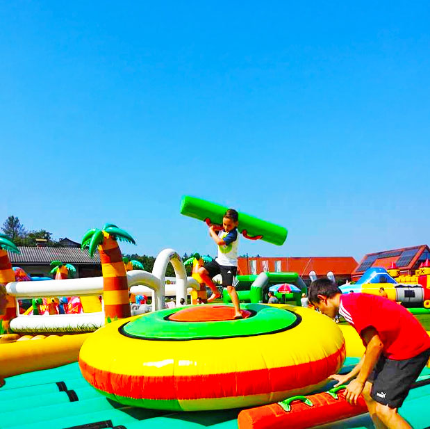 Kleiner Junge mit einem gruenen gepolsterten Stab in den Haenden in der Mitte einer Farbenfrohen Gladiatoren Arena