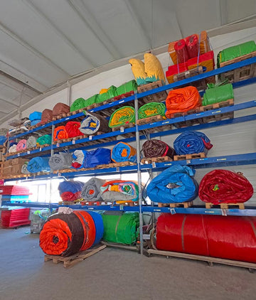 Viele eingerollte Hüpfburgen lagern auf einem Hochregallager.