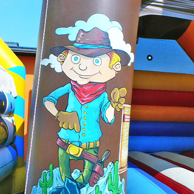 Freundlicher Cowboy mit Hut auf einer Saeule einer aufblasbaren Huepfburg.