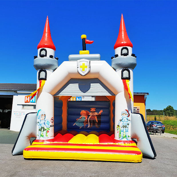 Aufblasbare Huepfburg im Ritterburg Design mit Tuermen, Figuren an den Saeulen und ein Bild an der Rückwand