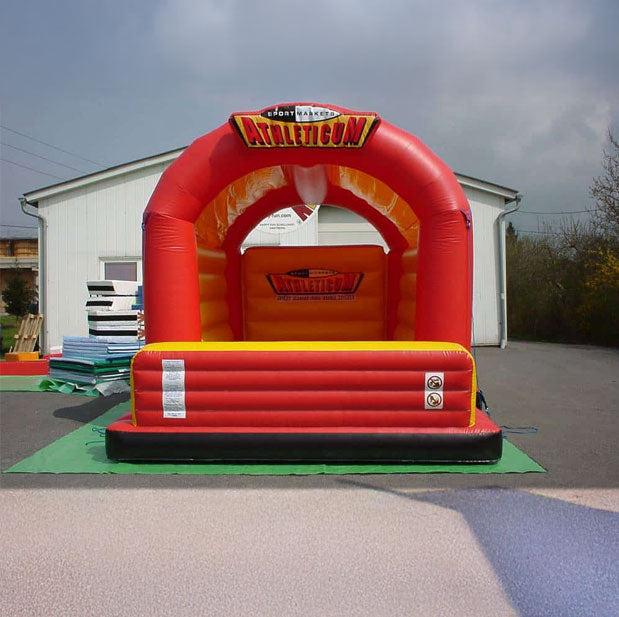 Hüpfburg in leuchtenden Farben  und einem Logo an der Rückwand vor einer Halle