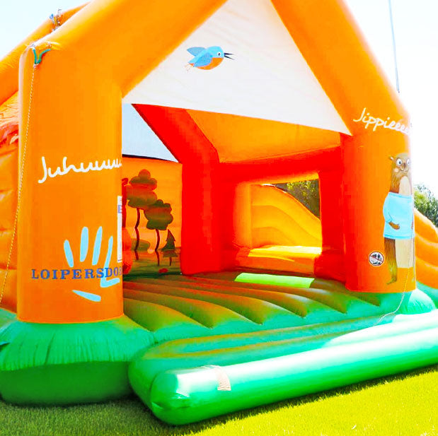 Hüpfburg in leuchtenden Farben mit Tieren auf einer Wiese