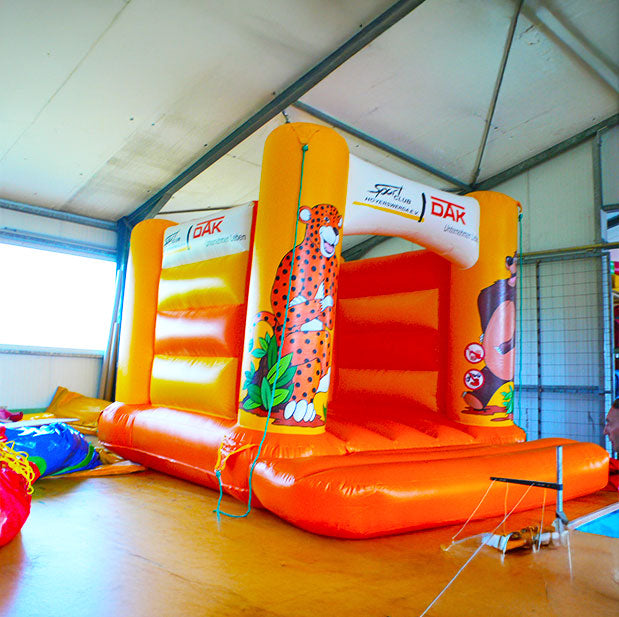 Hüpfburg in leuchtenden Farben von der Seite in einer Halle mit weißem Dach