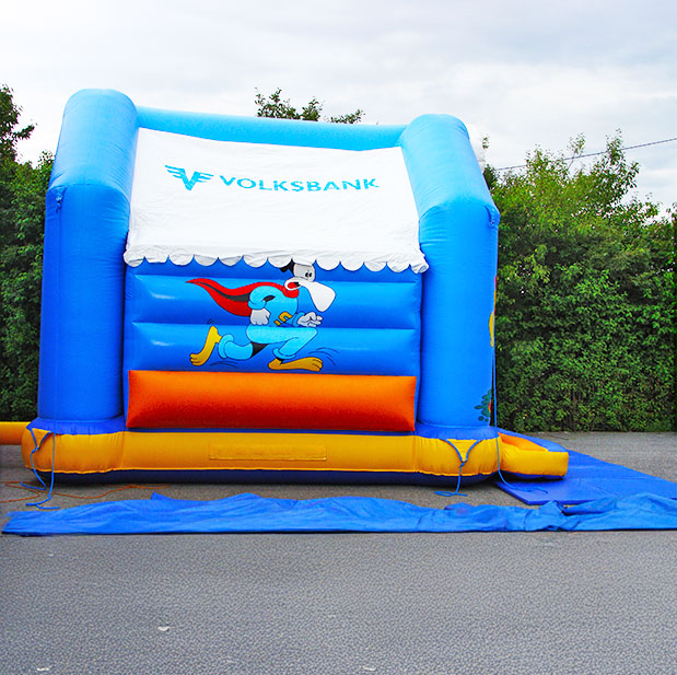 Hüpfburg mit Logo an der Seitenwand vor Büschen
