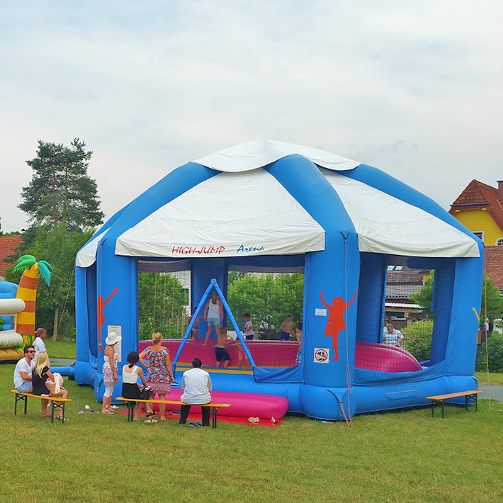 Kinder in einer High Jump Arena die im freien neben einer Huepfburg steht.