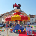 Farbenfrohes Karussell mit zehn Sitzen auf einem Stadtplatz eingezaeunt von einer Wimpelkette.