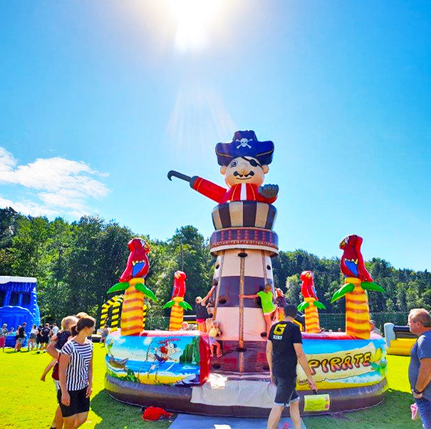 Pirat Kletterturm mit Papageien und Palmen in leuchtenden Farben umgeben von froehlichen Kindern und Erwachsenen