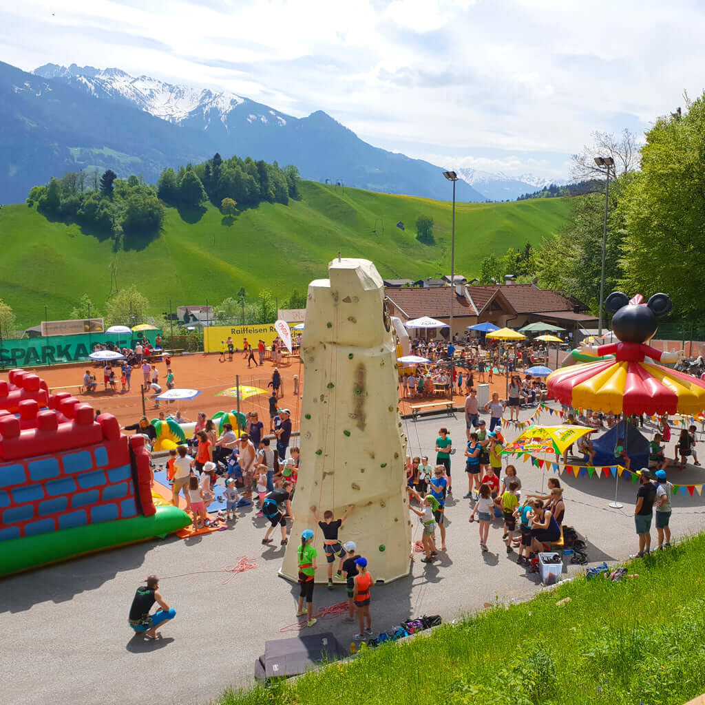Eine Veranstaltung mit vielen Besuchern und zentral einem Kletterturm.