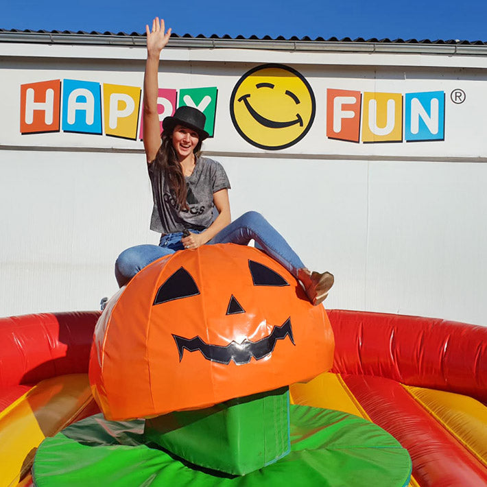 Froehliche Frau mit Hut auf einem Kuerbis-Rodeo mit Fallbecken.