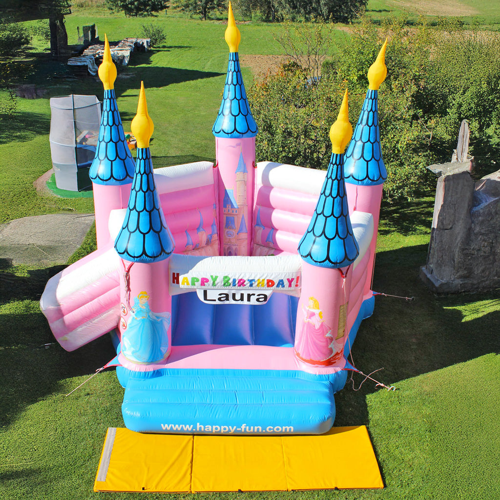 Eine Geburtstagshüpfburg in Rosa mit Spitzen Türmen sowie aufgemalten Prinzessinnen und einem Schloss.