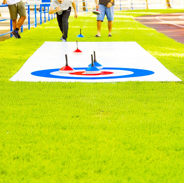 Menschen die auf einer gruenen Wiese ein Eisstockturnier spielen
