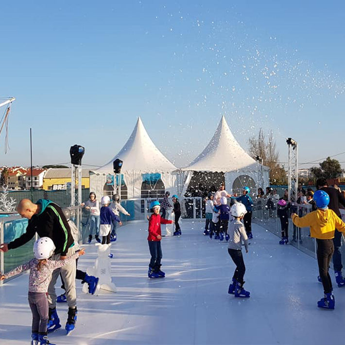 Ein Eislaufplatz steht draußen und wird von vielen Menschen befahren.
