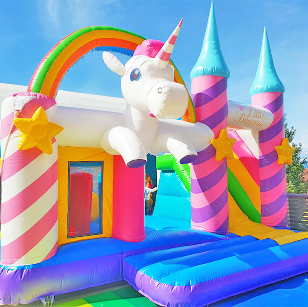 Huepfburg mit einem aufblasbarem Einhornkopf mit einem Regenbogen darueber in leuchtenden Farben