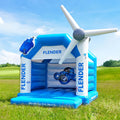 Aufblasbare Hüpfburg in Blau und Weiß mit dem Aufdruck „Flender“, dekoriert mit einem Windrad auf einer grünen Wiese bei Sonnenschein.
