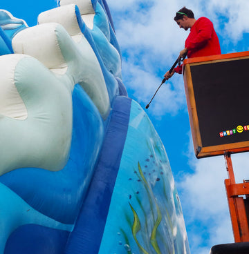 Eine aufblasbare, verschmutzte Hüpfburg wird mit einem Hochdruckreiniger gereinigt.