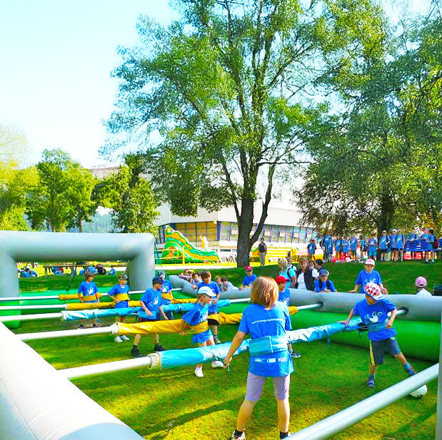 Froehliche Kinder die in einem aufblasbaren Riesenwuzzler festgegurtet sindauf einer gruenen Wiese