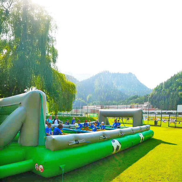 Aufblasbarer Riesenwuzzler zum mieten in leuchtenden Farben mit spielenden Kindern und zwei aufgemalte Fussbaelle auf der Seite