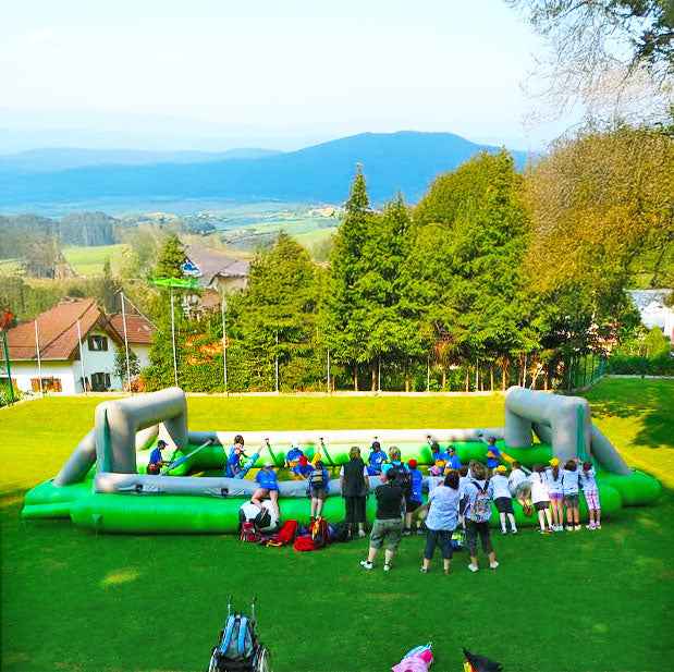 Viele Kinder bei einem Riesenwuzzler die bei einem Spiel im Freien zusehen