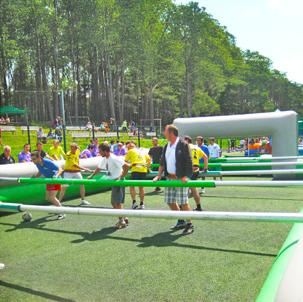 Erwachsene in einem Gruen-Grauen Riesenwuzzler auf einer gruenen Wiese.