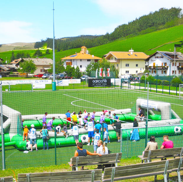 Aufblasbarer Riesenwuzzler zu mieten in Gruen-Grau auf einem Fussballfeld mit vielen Menschen