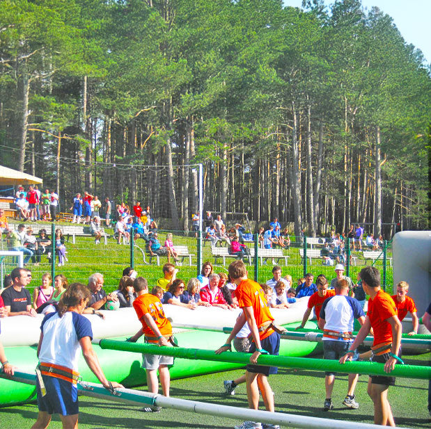 Menschen in einem Riesenwuzzler die an Stangen festgebunden sind mit vielen Zuschauern im Freien