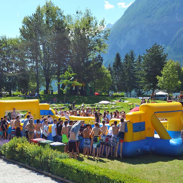 Riesenwuzzler zum mieten auf einer Wiese mit Teilnehmern und Zuschauern in Gruen-Gelb gehalten.