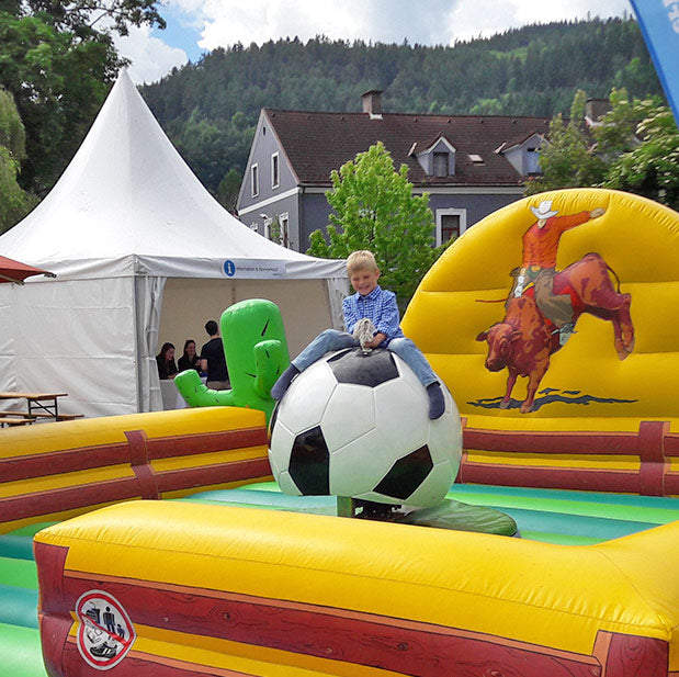 Froehlicher Junge auf einem Fussball-Rodeo neben einem Weissen Zelt.