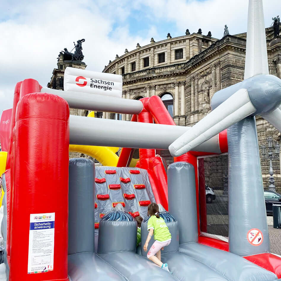 Aufblasbare Kletter- und Spielstation im Sachsen Energie-Design mit Windrad - ideal für Events im Zeichen von Nachhaltigkeit und Energieerlebnis.