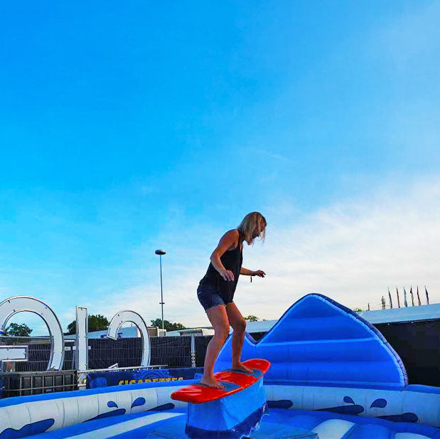 Junge Frau auf einem roten Surfboard eines Surf Rodeos im Freien