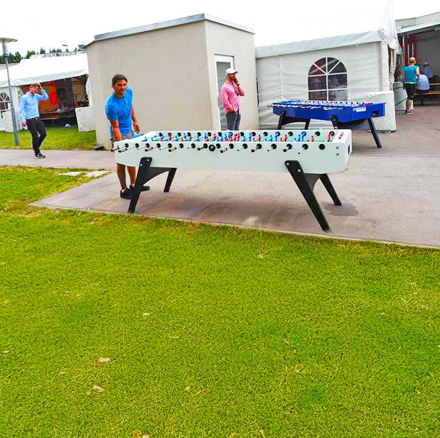 Ein Erwachsener Mann bei einem 8er Tischwuzzler der auf einem Betonplatz steht in Weiss-Schwarz gehalten