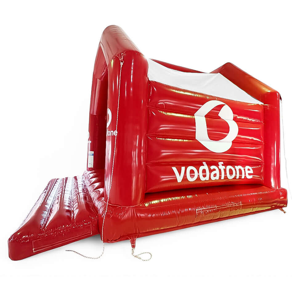 Seitlich abgebildete Vodafone-Hüpfburg in kräftigem Rot - ideal für Firmenveranstaltungen, Messen und aufmerksamkeitsstarke Promotion-Aktionen.