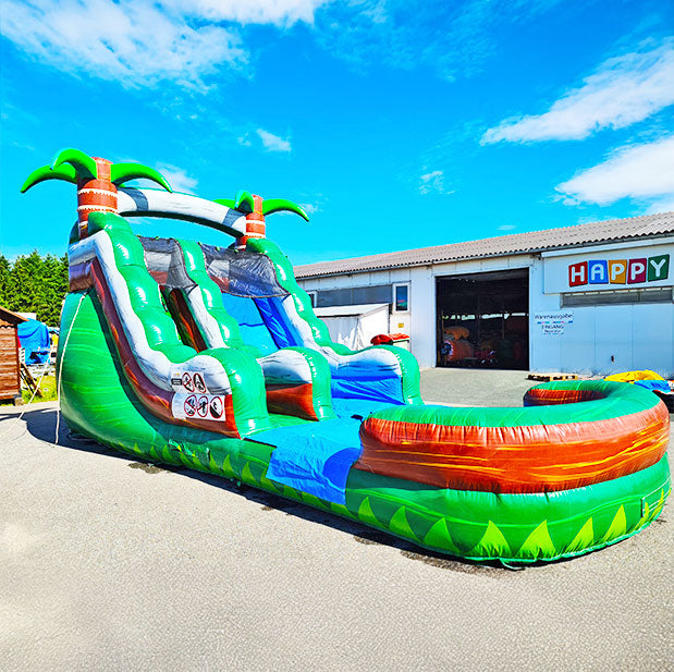 Wasserrutsche mit Auffangbecken, einem Aufstieg und Palmen vor einer Halle