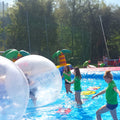 Becken mit Wasser und ein Team von Angestellten die große aufgeblasene Bälle mit Kindern darin, aus dem Wasser rollen.