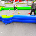 Zwei Maenner die in einem aufblasbaren Fussball-Billiard spielen der auf einem Betonboden steht.