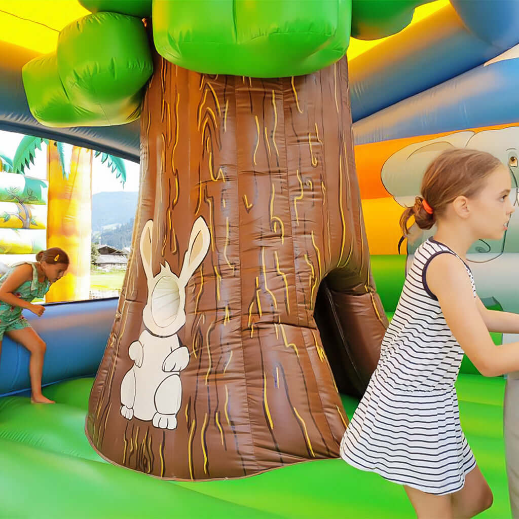 Fröhliche Spielszene in einer bunten Hüpfburg mit liebevoll gestaltetem Baumstamm und niedlichem Hasenmotiv - ideal für Kinderfeste und Events.