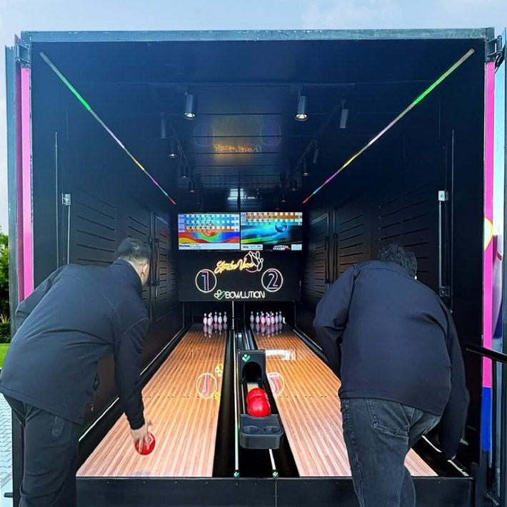 Zwei Maenner spielen in einer Mobilen Bowling Anlage.