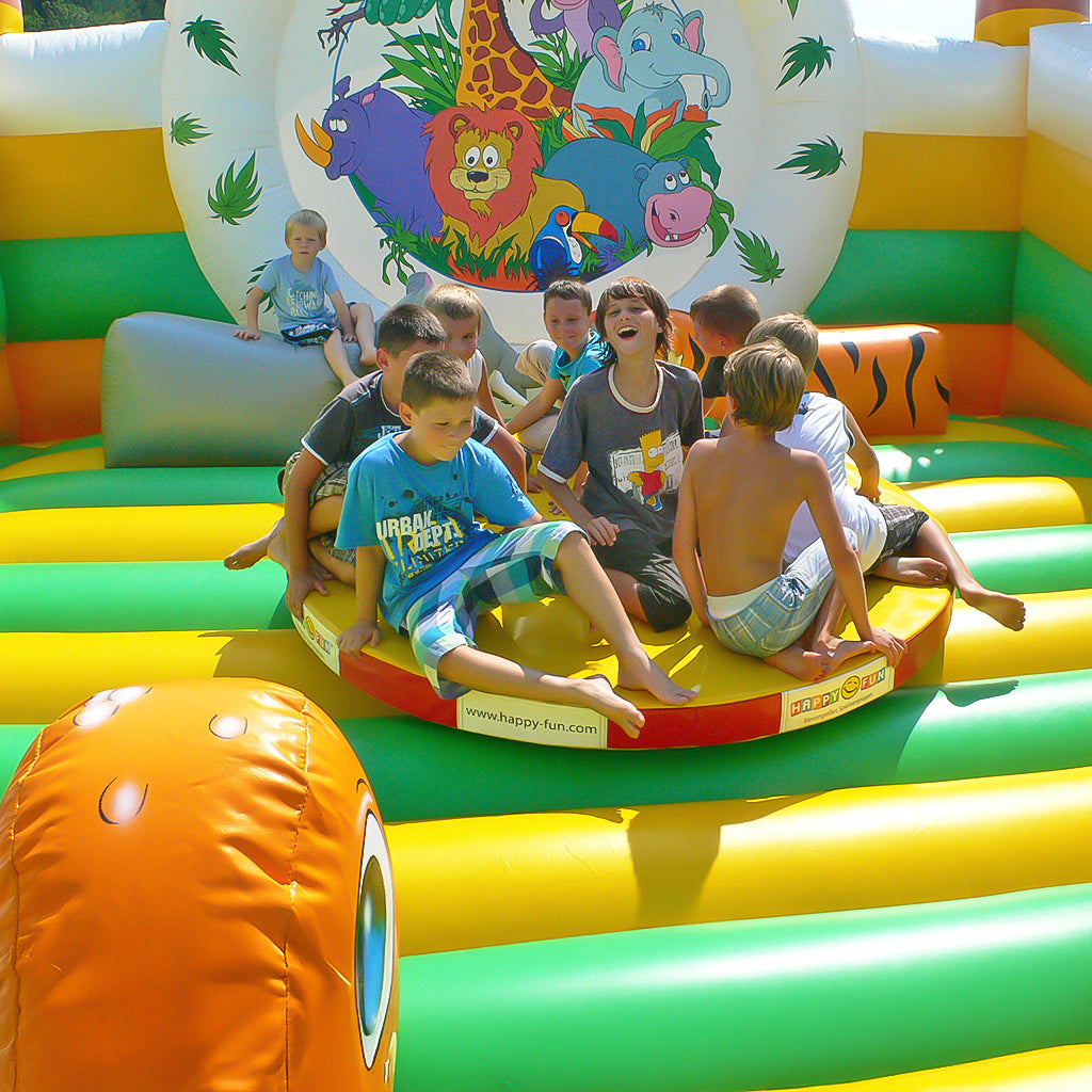 Kinder spielen in einer Hüpfburg auf einer Drehscheibe.