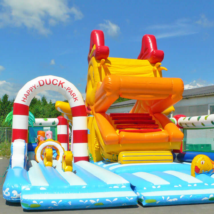 Frontansicht Aufblasbare Hüpfburg Ente Snappy Super mit Riesenrutsche, Entenkopf-Design, Palmen und Wasserpark-Elementen – bunter Spielspaß für Kinder