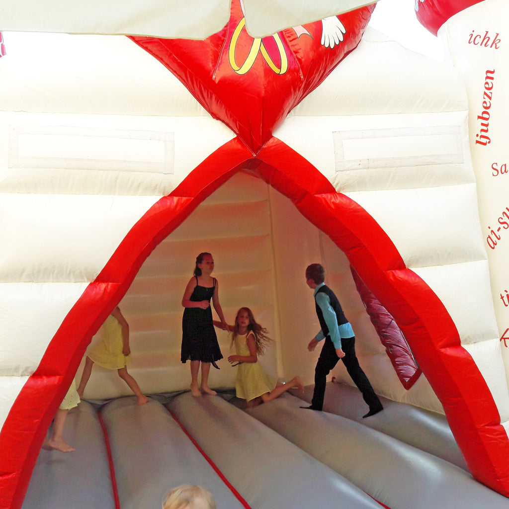 Einstieg und Sprungfläche einer Hüpfburg mit weis-rotem Eingang.