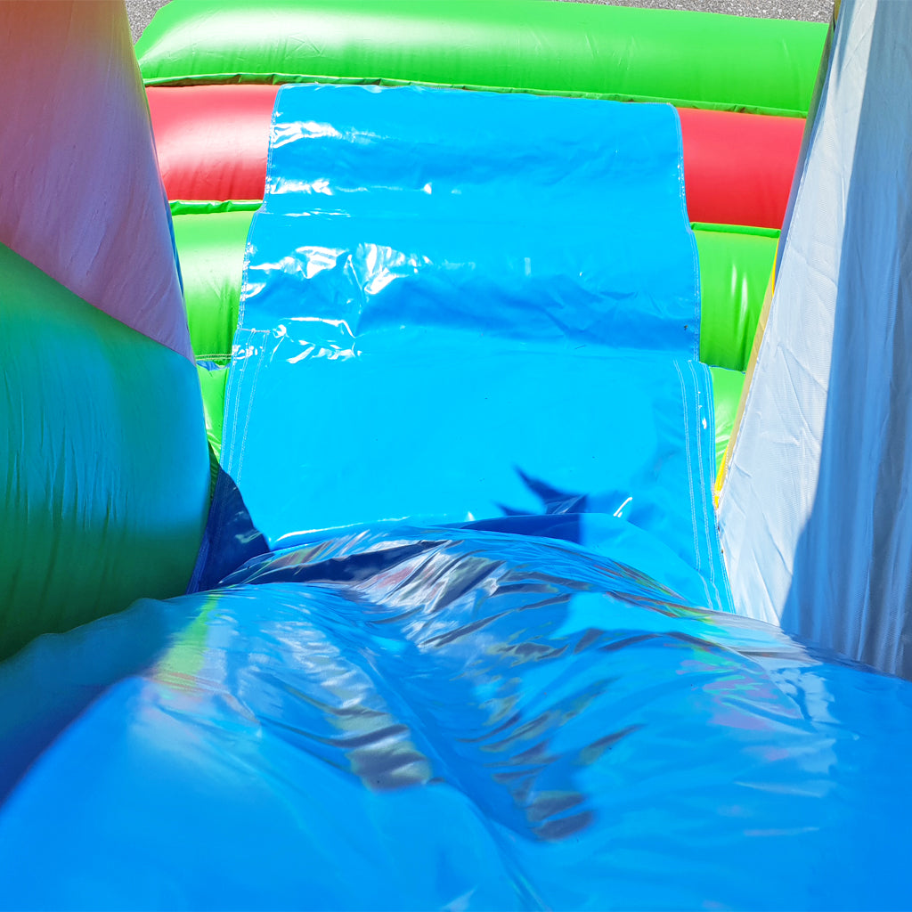 Eine Rutsche von einer Hüpfburg, mit grün-orangen Wänden.